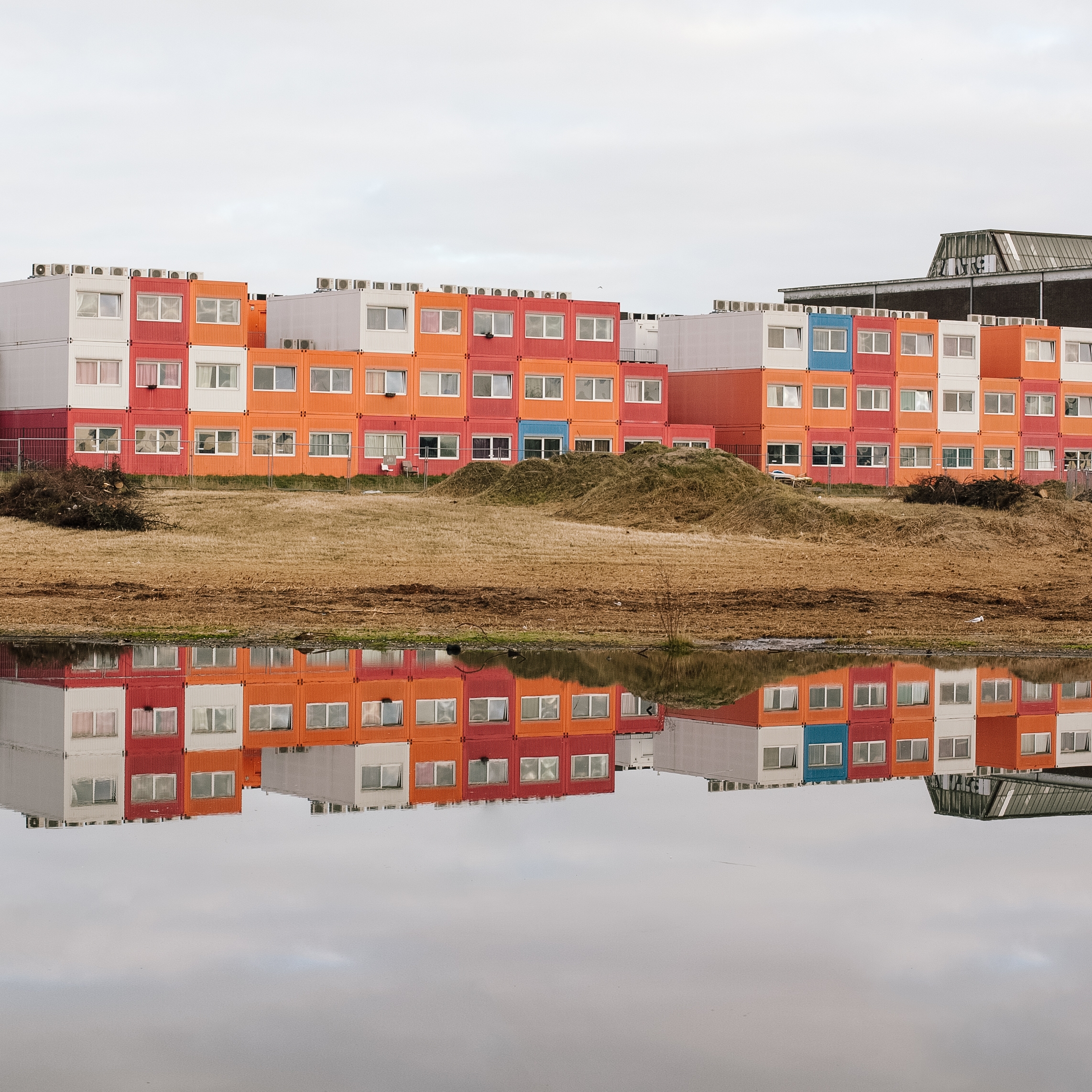 Colourful container homes reflected in water